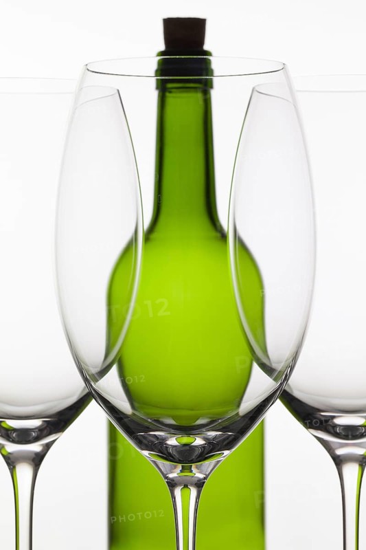 Three empty glasses of wine and green bottle on the white background