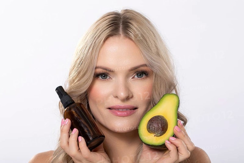 A model elegantly showcasing avocado along with beauty oil specifically designed for natural skincare routines