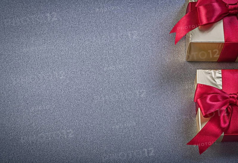 Boxed wrapped presents with red tapes on grey background copy space holidays concept