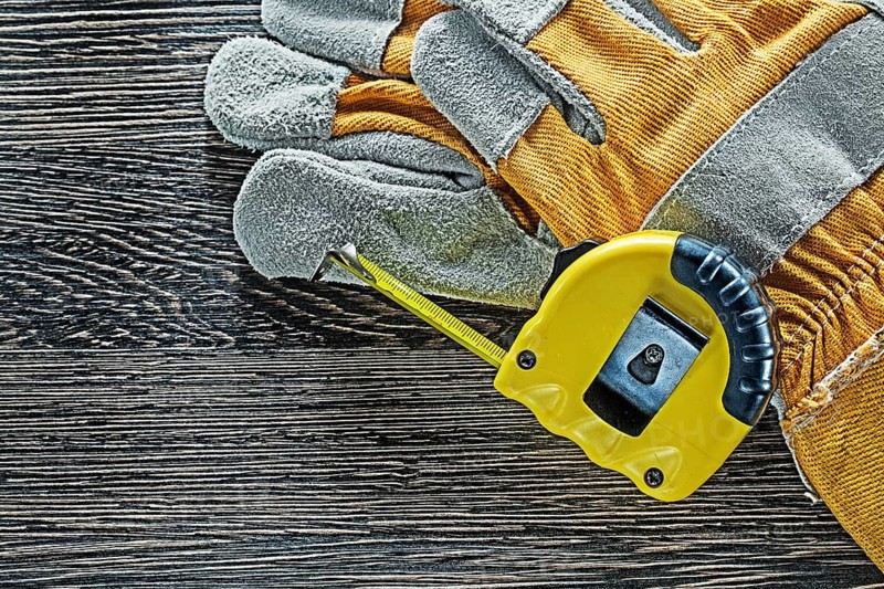 Tape measure pair of protective gloves on wooden board
