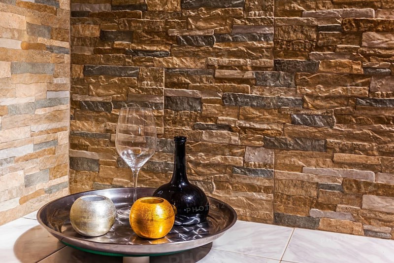 Still-life with a black glass jug, a transparent glass and two candlesticks. Background stone wall. Concept of artistic photography