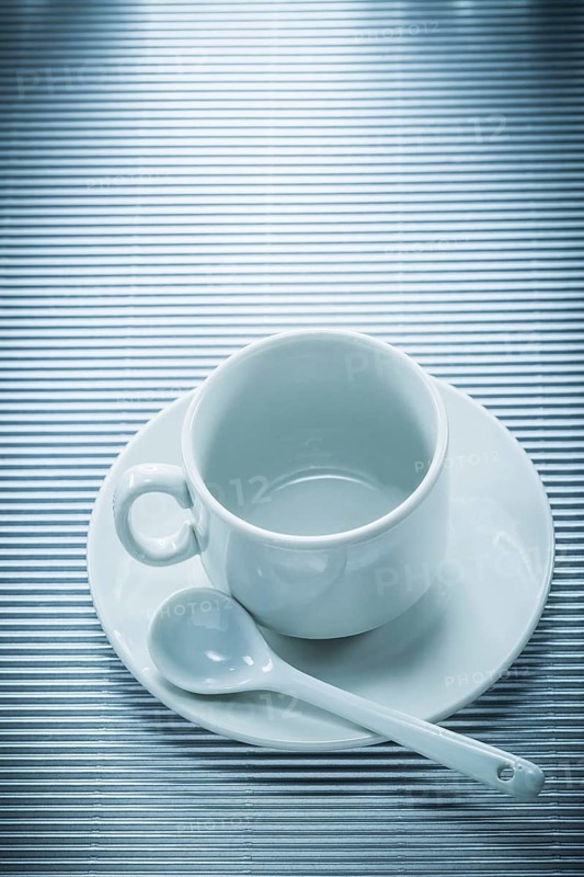 White ceramic cup saucer teaspoon on striped background