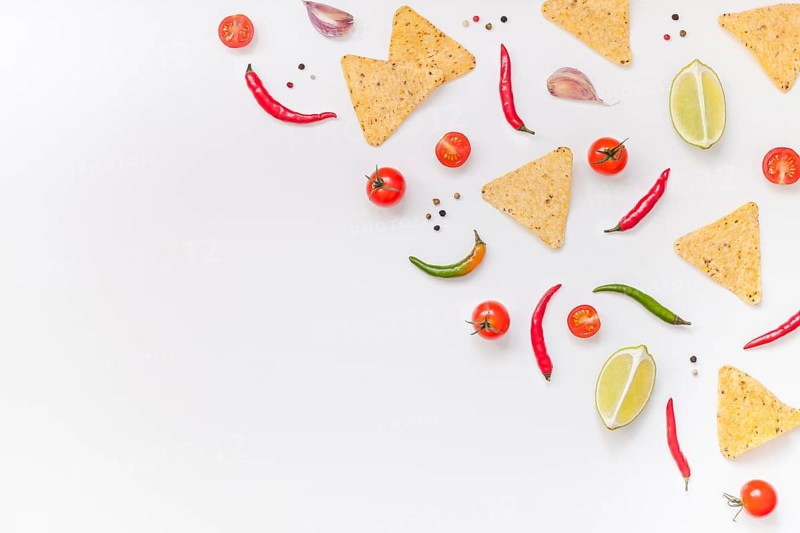 Creative Top view flat lay of fresh mexican food ingredients with tortilla nachos chips garlic pepper lime tomatoes on white table background with copy space. Food preparation cooking concept frame
