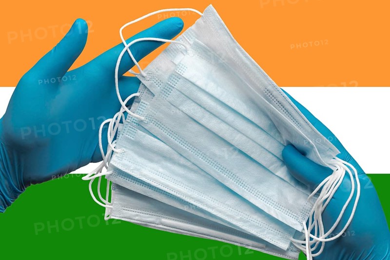 Doctor holding face masks in hands medical blue gloves on background national flag of India. Concept coronavirus quarantine, pandemic outbreak, grippe, hygiene. Surgical antibacterial face bandage