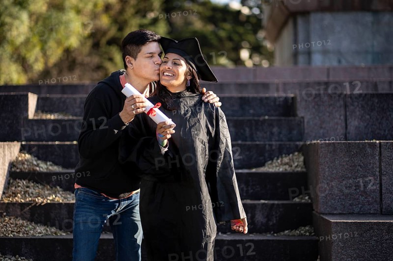 Transgender woman recent graduated, dressed in cap and gown, showing off his degree celebrating with her family