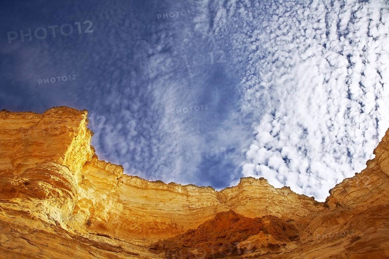 Edges of a canyon from dry sandstone on a background of the cloudy sky
