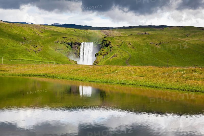 An incredible reflection. Abounding waterfall Skogafoss reflected in a small pond near the road