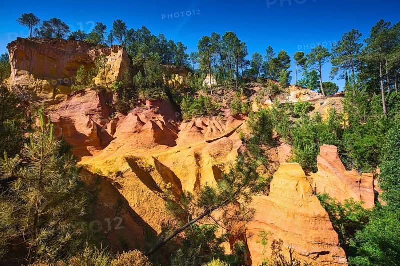 Unique red and orange hills in the province of Languedoc - Roussillon, France. Green trees create a beautiful contrast with the bright ocher