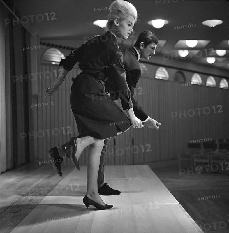 Dancing in the 1960s. The dance Hully Gully is being made popular and here are men and women dancing the new craze. Hully Gully was a type of unstructured line dance and consisted of a series of steps and was relatively simple and easy to execute. Hully Gully can be seen performed by actor John Belushi in the film Blues Brothers. Notice the typical BeeHive hairdo on the girl in front. Picture taken 1963