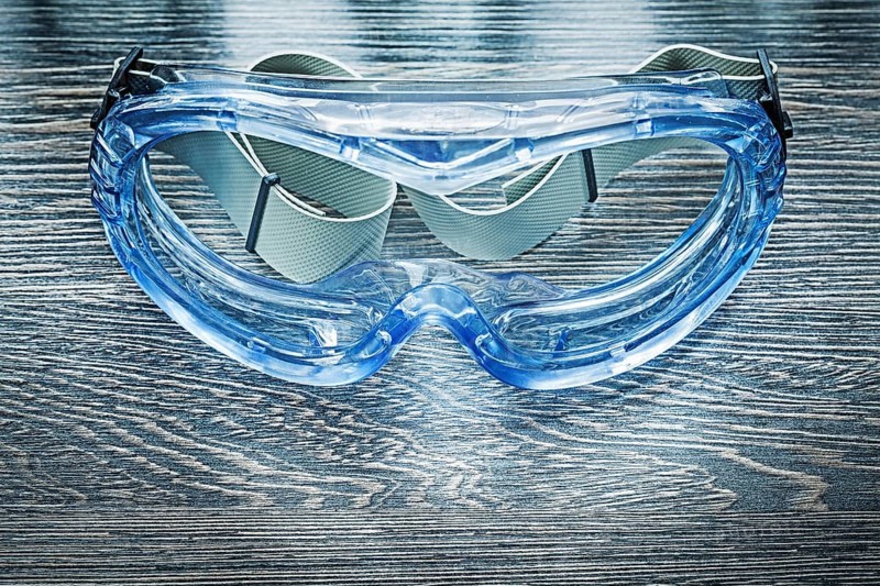 Safety plastic goggles on wooden board