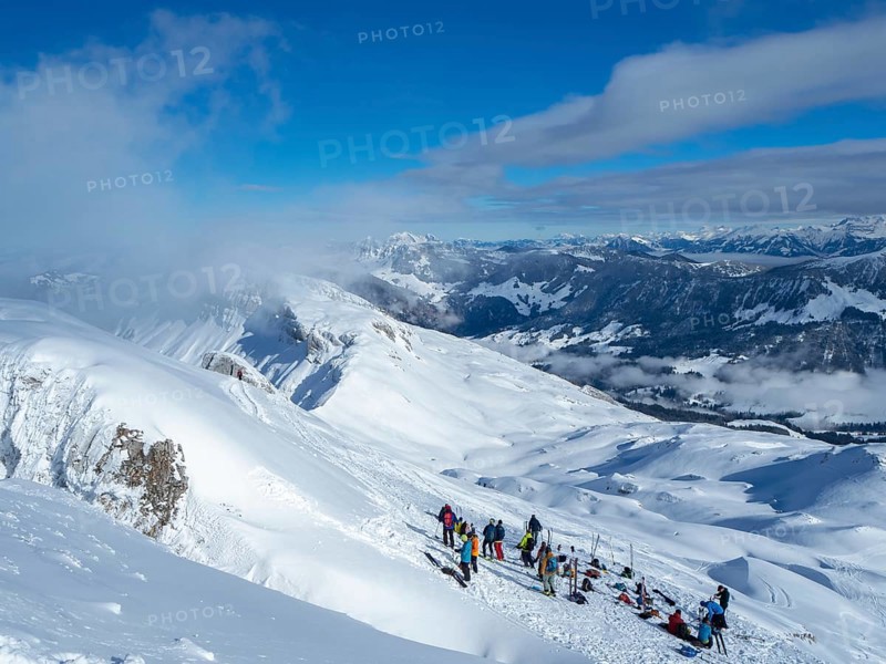 Situation on the summit of Haengst in Soerenberg, Switzerland, on a sunny winter day: A group of ski tourers having a rest