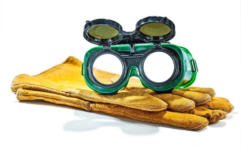 Welder working goggles on pair of gloves isolated