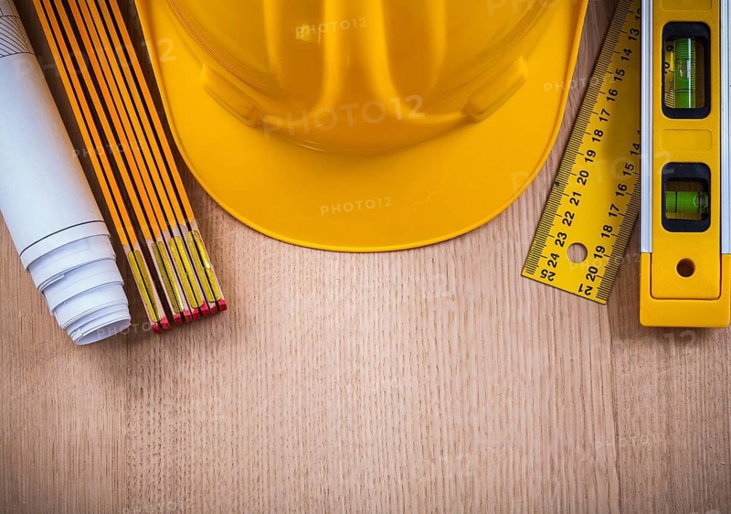 Protective helmet instruments of measurement blueprints and construction level on wooden board architecture and building concept