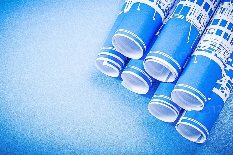 Stack of engineering drawings on blue background top view