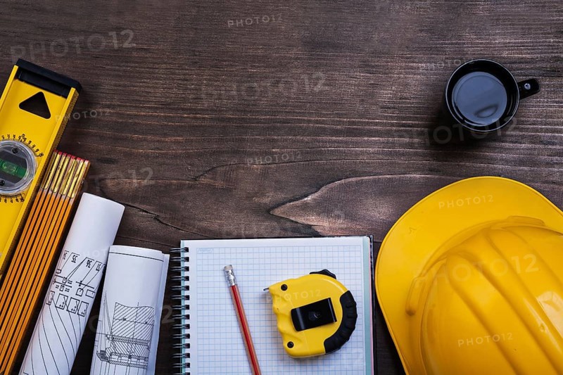 Workbook pencil cup of coffee and construction objects on wooden board maintenance concept