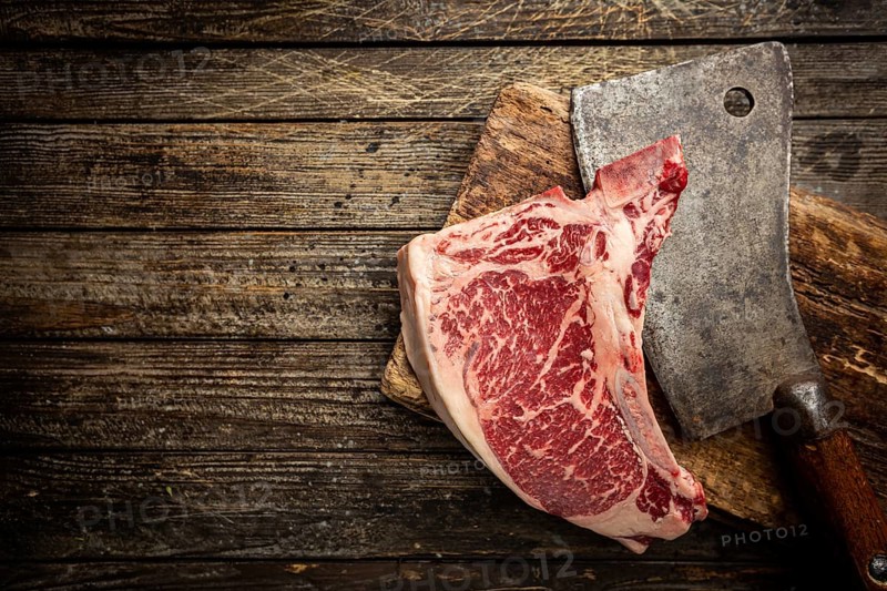 Raw fresh meat T-bone beef Steak and butcher knife on wooden background, top view
