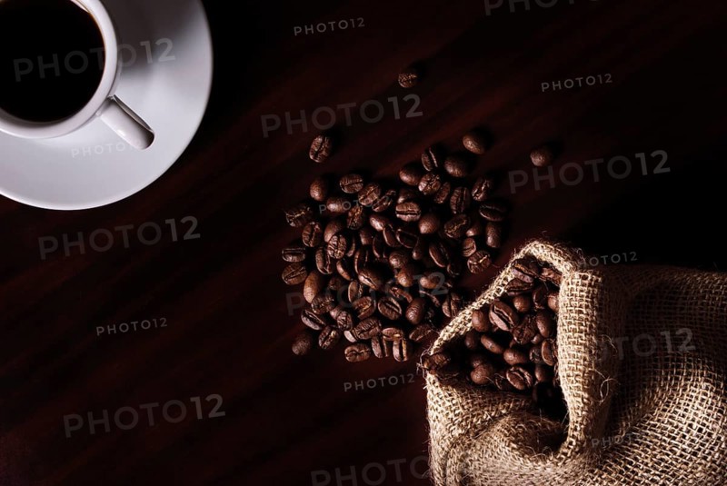 Coffee still life with cup, coffee beans in bag. Low key light