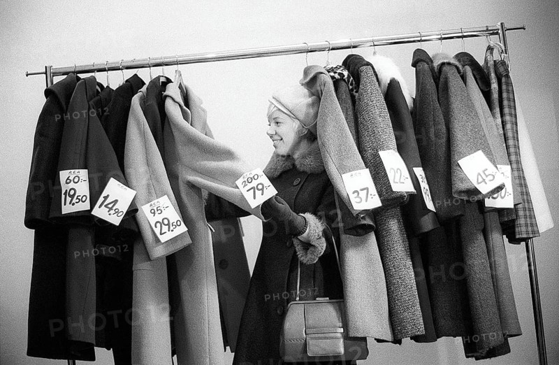 Great discounts of outerwear in the 1960s. A woman stands by a clothes rack, choosing from outerwear and coats marked with price tags with discounted prices. Judging by her face, she appreciates the reduced prices and thinks she's getting real bargains. Sweden January 1963. Ref CV28