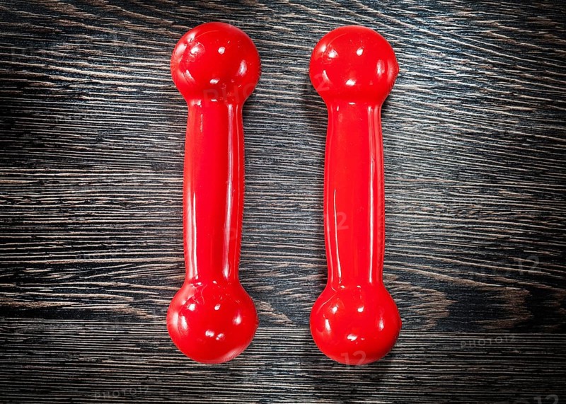 Red dumbbells on vintage wooden board