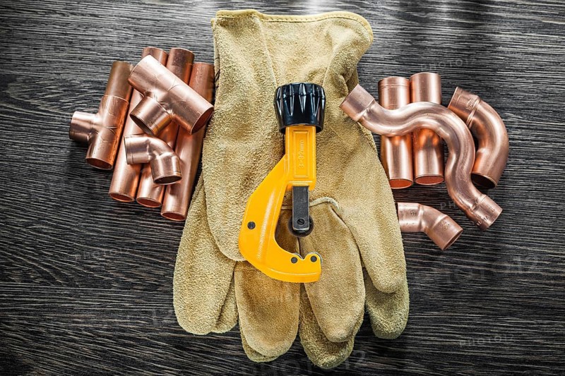 Plumbing water pipe scissors leather safety gloves on wooden board top view
