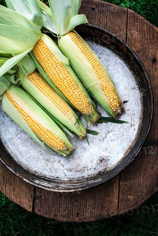 Raw corn in the garden on wooden background