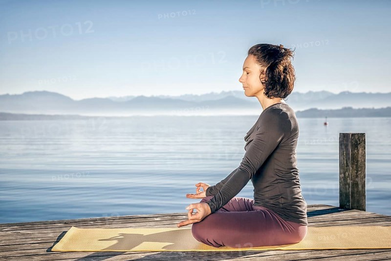 A pretty woman doing yoga at the lake
