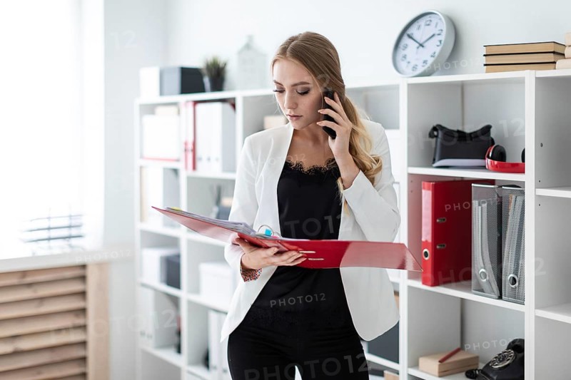 Beautiful young girl with blond hair in a white jacket and black blouse is working in the office. photo with depth of field
