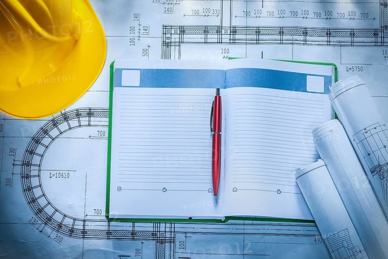 Pen hard hat construction drawings notepad on blueprint