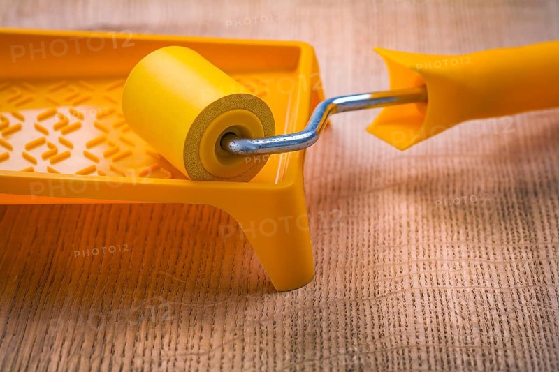 Roller on paint tray and wooden board