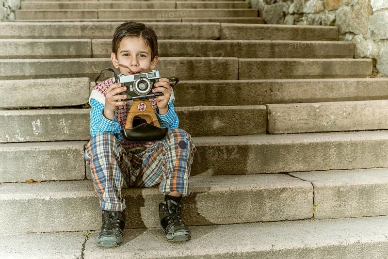 Child with vintage camera. Exterior stairs