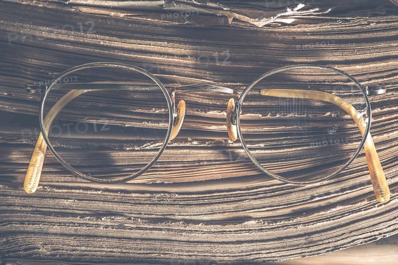 Old vintage round glasses and old book. Low light