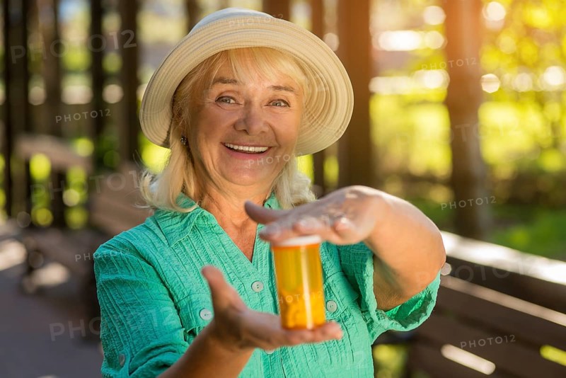 Smiling lady with pill bottle. Senior woman holds medicine. Good health and strong immunity. Most effective drug