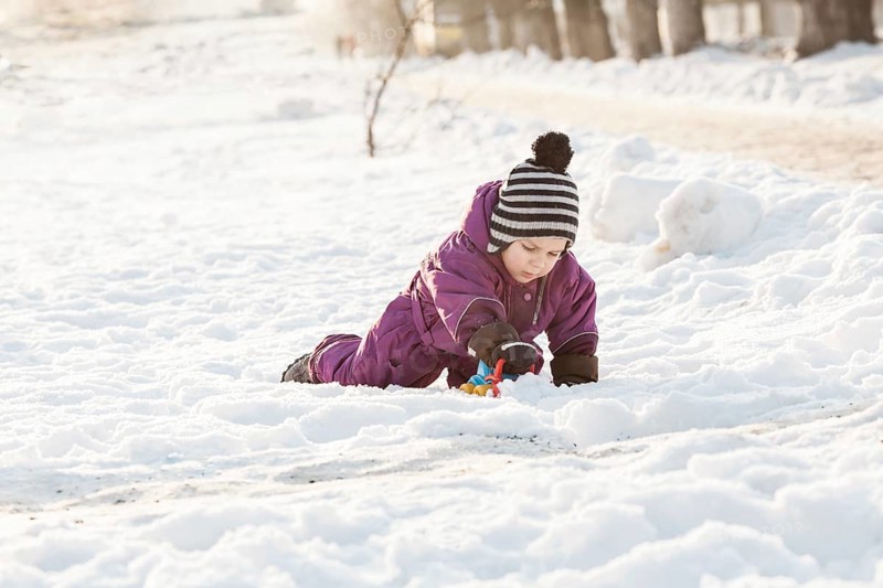 Boy playing with snowplow toy. Cold winter day
