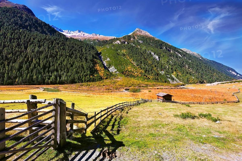 The beautiful autumn day in the Austrian Alps. Farmers alpine meadows blocked by low wooden fences