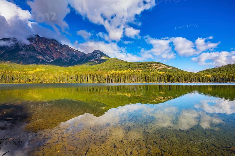 Frosty morning in the Rocky Mountains, Canada. Clear water Pyramid Lake reflects the clouds and pine forests on the shore