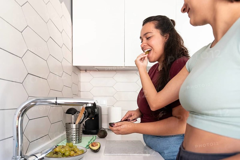A cheerful lesbian couple shares a coffee break in their stylish kitchen. They enjoy a moment of laughter and connection, creating a relaxed, happy atmosphere