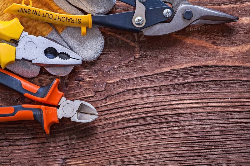Nippers pliers wire-cutter and construction glove on wood board maintenance concept