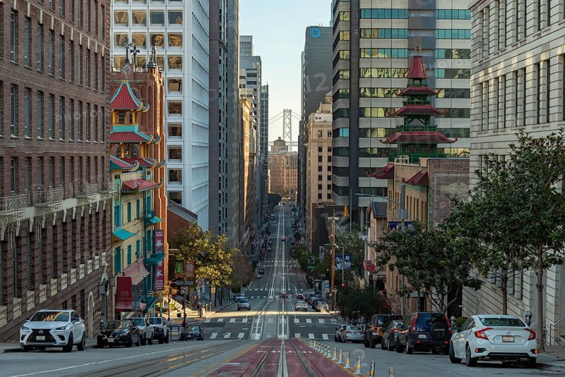 A picture of the long California Street, with Downtown San Francisco and the Oakland Bay Bridge at the far center. On the foreground there's also Chinatown