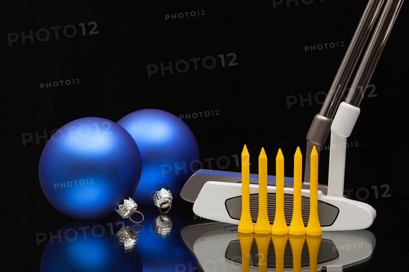 Christmas decoration and two golf putters on a glass desk