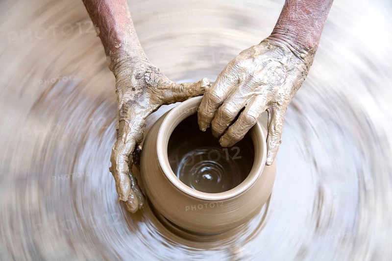 Pottery, artist muddy hands making clay pot giving shape on spinning wheel, semi urban village Dilwara, Udaipur, Rajasthan, India