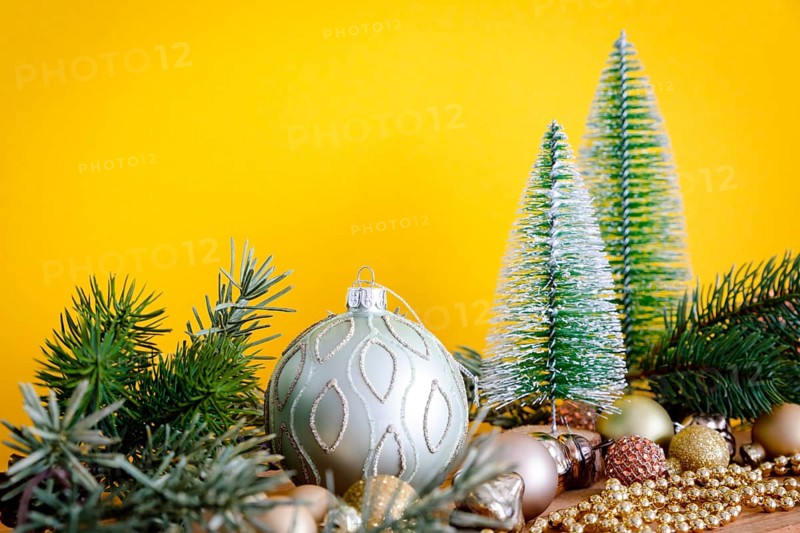 A Christmas decoration glass balls with fir trees on yellow background