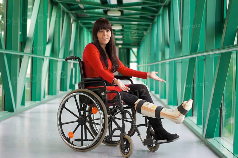 Young woman with plaster leg sits in a wheelchair Austria