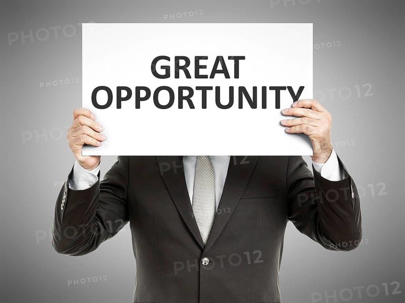 A business man holding a paper in front of his face with the text great opportunity