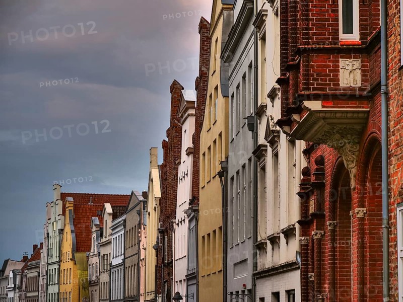 A row of historic red brick buildings under a cloudy sky, gothmund, travemünde, lübeck, germany