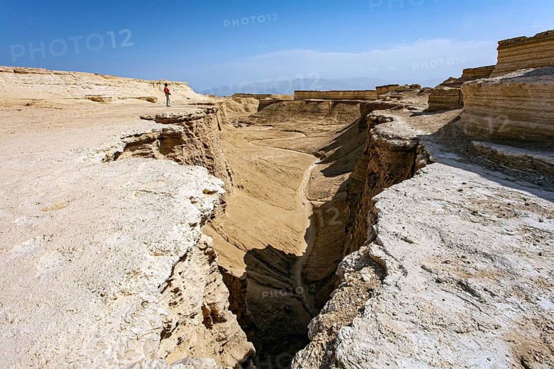 Woman tourist in a red sweater admires the landscape. The Judean Desert. Israel. Interesting walk among picturesque hills, cliffs and limestone gorges. Dead Sea