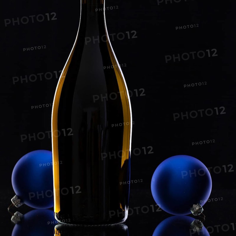 The bottle of red wine and Christmas decoration on a black glass desk