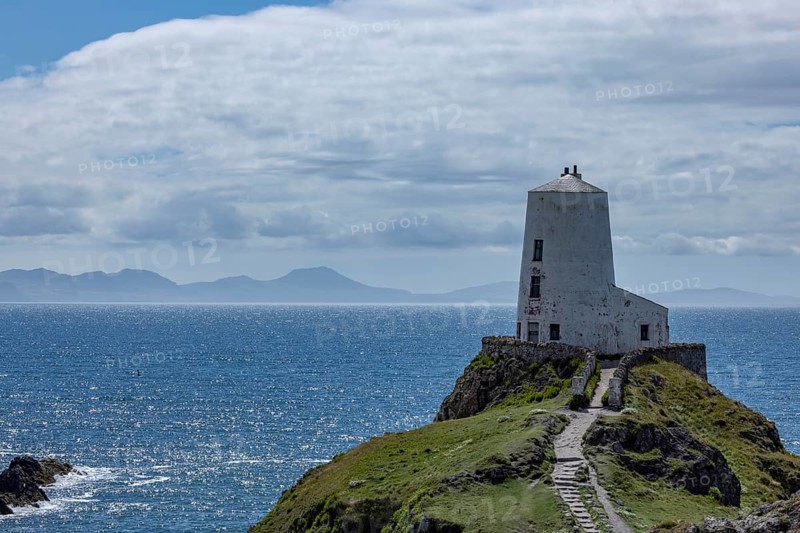 Twr Mawr Lighthouse, white lighthouse on a hill by the sea with blue sky and clouds, Ynys Llanddwyn, Newborough, Anglesey, Wales, Great Britain