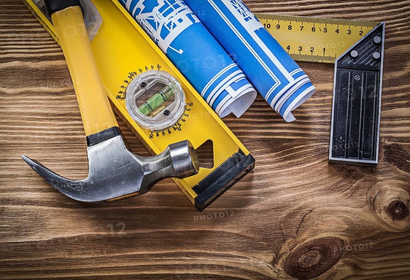 Blue blueprints construction level try square claw hammer on wooden board
