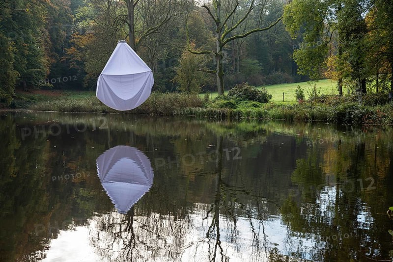 Reflecting water pond in a park with a white bed sheet hanging in a tree