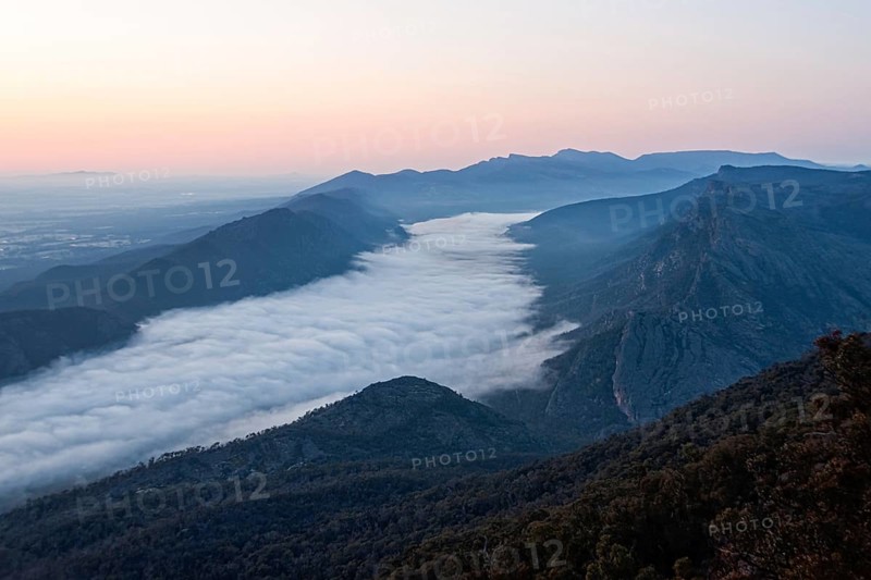 Clouds in the valley and the Wonderland Range at sunrise photographed from the Boroka Lookout in the Grampians, Victoria, Australia